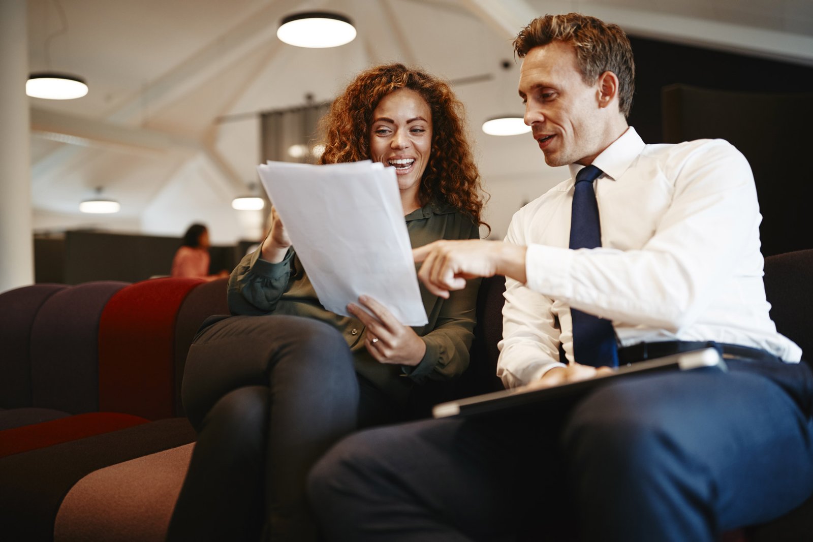 two-smiling-businesspeople-sitting-in-an-office-di-DQ6MRX8.jpg